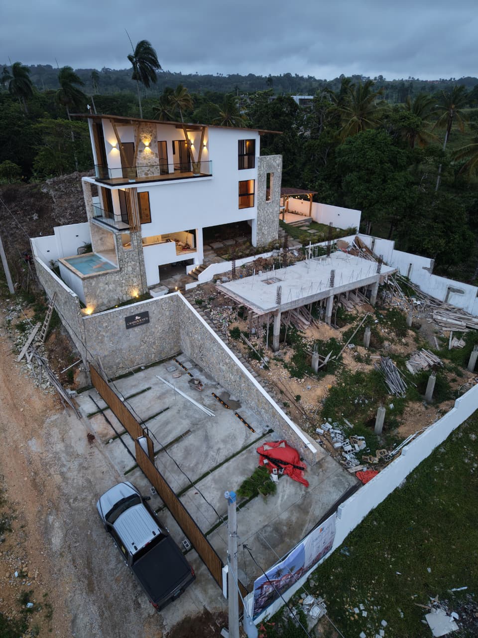 Villa en colina en construcción al atardecer, con niveles terminados junto a una losa abierta
